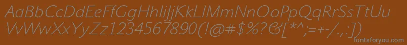 JohnsansWhiteProItalic-fontti – harmaat kirjasimet ruskealla taustalla