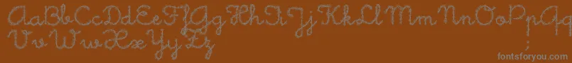LittleDaisy-fontti – harmaat kirjasimet ruskealla taustalla