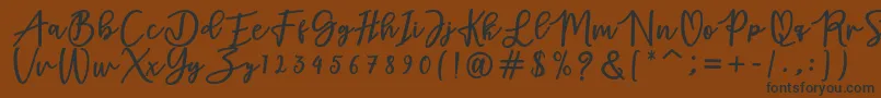 フォントadamd – 黒い文字が茶色の背景にあります