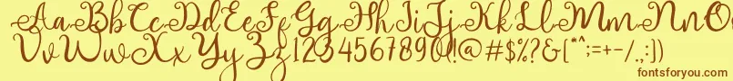 フォントadhellita – 茶色の文字が黄色の背景にあります。