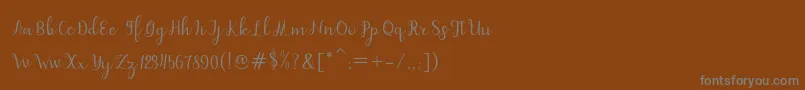 dahlia script-fontti – harmaat kirjasimet ruskealla taustalla
