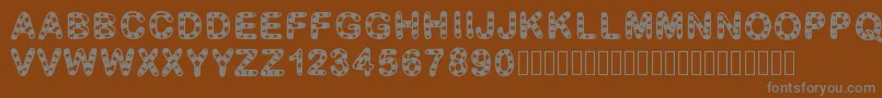 GaelleFont12-fontti – harmaat kirjasimet ruskealla taustalla