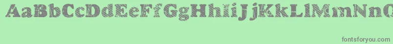 Goodjean-fontti – harmaat kirjasimet vihreällä taustalla