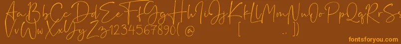 フォントRushtick – オレンジ色の文字が茶色の背景にあります。