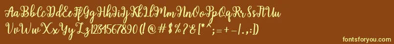 Shaila Script-fontti – keltaiset fontit ruskealla taustalla