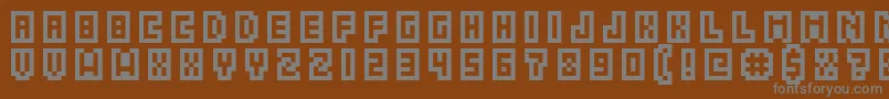 GrixelAcme5CompcapsoXtnd-fontti – harmaat kirjasimet ruskealla taustalla