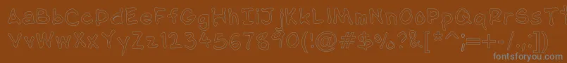 NipcensHandwritingOutline-fontti – harmaat kirjasimet ruskealla taustalla