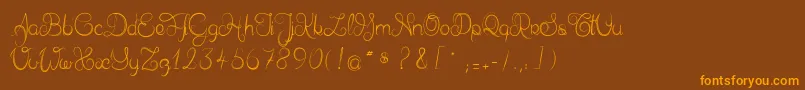 フォントDelphineetmathiasscript – オレンジ色の文字が茶色の背景にあります。