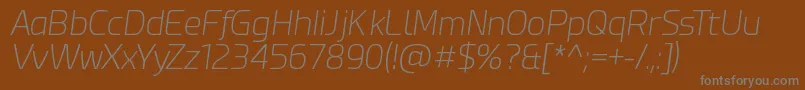 EsphimereExtraLightItalic-fontti – harmaat kirjasimet ruskealla taustalla