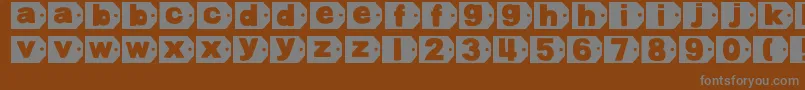 DjbTaggedAgain-fontti – harmaat kirjasimet ruskealla taustalla