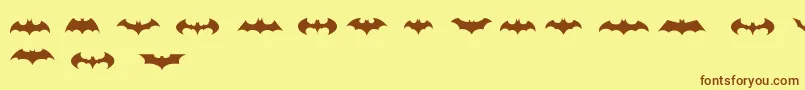 フォントBatmanLogoEvolutionTfb – 茶色の文字が黄色の背景にあります。