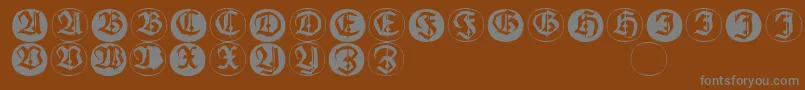 Frakturinitialenangularround-fontti – harmaat kirjasimet ruskealla taustalla
