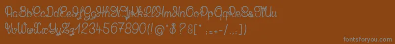 MandalaHome-fontti – harmaat kirjasimet ruskealla taustalla